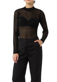 Czarny prążkowany top z długim rękawem i wysokim kołnierzem, z przezroczystym materiałem i dopasowanym krojem biustu, w zestawie z czarnymi eleganckimi spodniami.