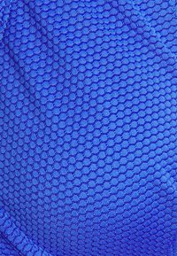 Tecido azul texturizado com um padrão de favo de mel, apresentando uma aparência suave e cor vibrante. As bordas são cosidas para maior durabilidade.