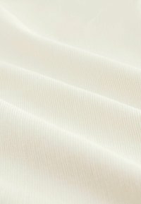 Tejido blanco acanalado con una textura suave. Presenta sutiles líneas de textura que corren horizontalmente. Apariencia suave, ligera y maleable.