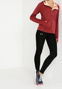 Giacca a zip color bordeaux con colletto rosa chiaro, leggings neri e scarpe da corsa grigio-neri con dettagli rosa. Tessuto liscio, vestibilità atletica.