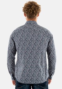 Langarmshirt in marineblauw met een bloemenpatroon. De stof is lichtgewicht met een soepele textuur. Het shirt heeft een klassieke kraag en knoopmanchetten.