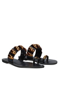 Sandalias planas negras con una tira ancha que presenta acentos metálicos dorados. Textura suave y diseño minimalista con una entrehuella de dedo.