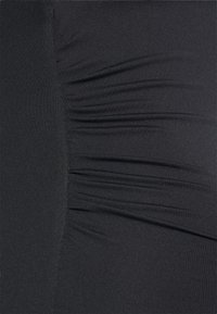 Schwarzer, eng anliegender Stoff mit geraffter Textur, vertikalen Linien und einem glatten, dehnbaren Aussehen.