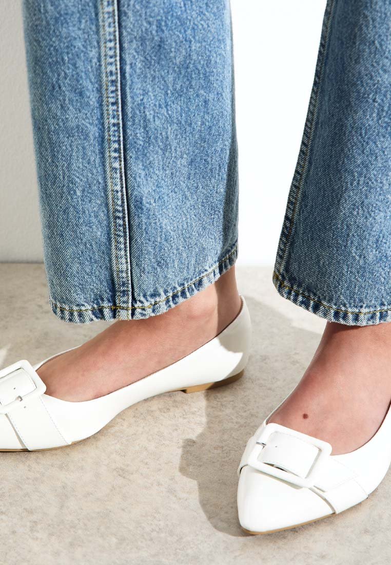 Vita läderballerinas med spetsig tå och en framträdande rektangulär spänne. Bärs med ljusblå vida jeans.