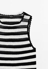 Haut sans manches en maille avec des rayures horizontales noires et blanches et des bords festonnés autour de l'encolure et des emmanchures.