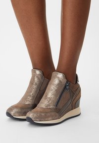 Hällsneakers i metallisk brons med släta och strukturerade ytor, utrustade med sidodragkedjor och en vadderad, lätt sula.