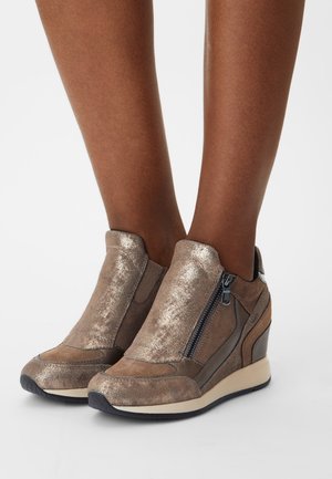 Stivaletti con tacco a cuneo in bronzo metallico con superfici lisce e testurizzate, dotati di cerniere laterali e una suola leggera e imbottita.