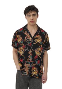 Czarna koszulka z krótkim rękawem, z żywym wzorem tigera i róż w kolorach żółtym, czerwonym i zielonym, wykonana z lekkiego materiału o luźnym kroju.