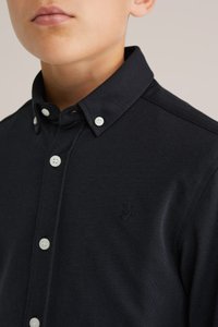 Tumši zils garo piedurkņu krekls, izgatavots no teksturēta auduma, ar pogājamu apkakli un baltām pogām, uz krūtīm ar izšūtu logotipu.