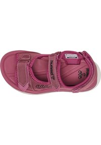 Różowe sandały z materiałowym wierzchem, posiadające regulowany pasek. Lekkie, wyściółkowane podeszwy z teksturowaną wkładką i wzorzystymi akcentami.