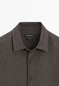 Brown textured collared shirt with button closure, featuring a subtle striped pattern and two black label tags inside the collar.