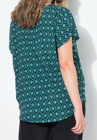 Haut teal à manches courtes avec un motif en diamant. Tissu doux, coupe décontractée et ourlet arrondi. Les accents comprennent une silhouette ample et un léger drapé.