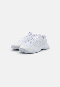 Białe sportowe buty z siateczkowej górnej części, tonalnymi trzema paskami i teksturowaną gumową podeszwą. Posiadają sznurówki i wyściółkę przy kołnierzu.