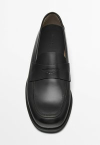 Schwarze Lederloafer mit einem breiten Riemen, runder Zehenform und minimalen Nähten. Glatte Textur, flache Sohle.