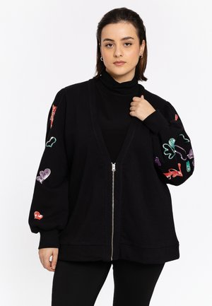 Black zip-up sweatshirt with a deep V-neck, featuring colorful, sparkly heart and animal motifs on the sleeves. Smooth texture and relaxed fit.