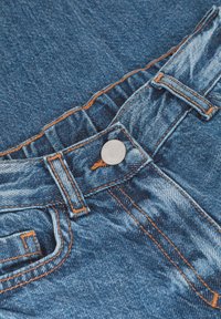 Jeans in denim con una lavatura blu media e cuciture arancioni, caratterizzati da un bottone in metallo e dettagli con elastico in vita.