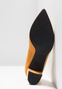 Chaussure en daim beige à bout pointu avec semelle noire embossée de motifs de pièces et marquage "KAISER", taille 41½, talon face vers l'avant.