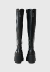 Zwarte leren kniehoge laarzen met zijritsen en chunky hakken, met een soepele textuur en een slank ontwerp, geschikt voor verschillende outfits.