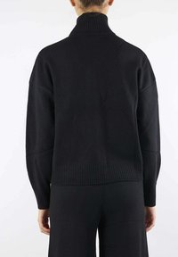 Maglione girocollo lavorato a maglia nera con orlo e polsini a costine. Vestibilità ampia e maniche lunghe, caratterizzato da una texture liscia e un design semplice.