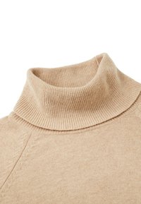 Pull en col roulé en tricot beige avec col côtelé et détails de côtes subtiles sur la couture de l'épaule.