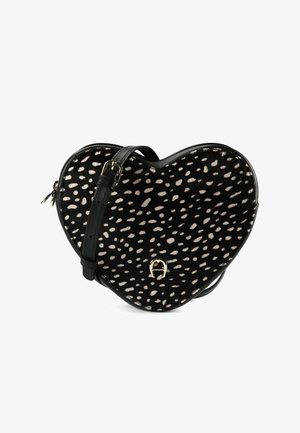 Heart-shaped handbag in black and white, featuring a spotted pattern, leather material, adjustable shoulder strap, and gold-tone hardware.