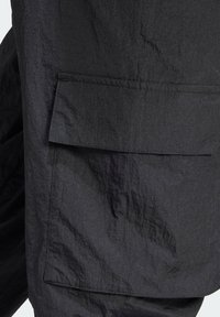 Svarta arbetsbyxor i stil med strukturerad tyg med en stor framficka. Har en avslappnad passform och subtila ytförändringar.