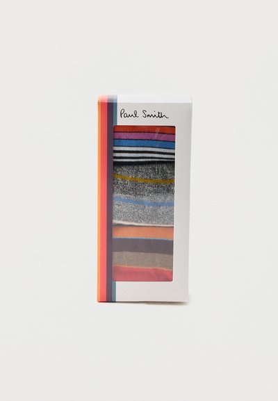 Ensemble de six chaussettes pliées colorées à rayures visibles à travers la fenêtre d'une boîte d'emballage blanche de la marque Paul Smith.