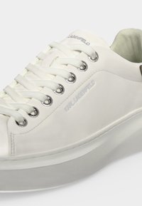 Λευκό sneaker χαμηλού τύπου με παχιά σόλα, λευκά κορδόνια μέσα από ασημένια οφθαλμάκια και σήμανση "Karl Lagerfeld" στο πλάι και στη γλώσσα.