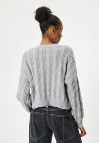 Grijs, kabelgebreid vest met een ontspannen pasvorm, voorzien van geribde manchetten en zoom, een cropped lengte en een gestructureerde afwerking.