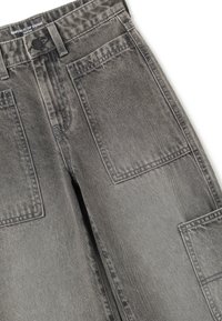 Pantalones cargo de mezclilla en gris deslavado. Presentan grandes bolsillos delanteros, un cierre de botón y un diseño clásico de pierna recta con tejido texturizado.