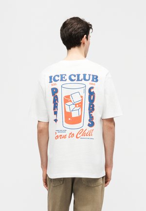 Mężczyzna w białej koszulce z kolorową grafiką szklanki z kostkami lodu i napisem „ICE CLUB PARTY CUBES Born to Chill” na plecach.