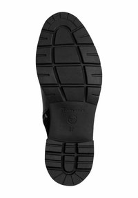 Semelle de chaussure noire avec une surface en caoutchouc texturé, présentant un motif de rainures et de crêtes pour plus d'adhérence. Marquée "Tamaris" et taille "37."