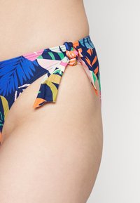 Parte de baixo de biquíni com padrão floral em azul-marinho, com designs de folhas multicoloridas, apresentando laços laterais com um detalhe de nó. Textura de tecido suave.