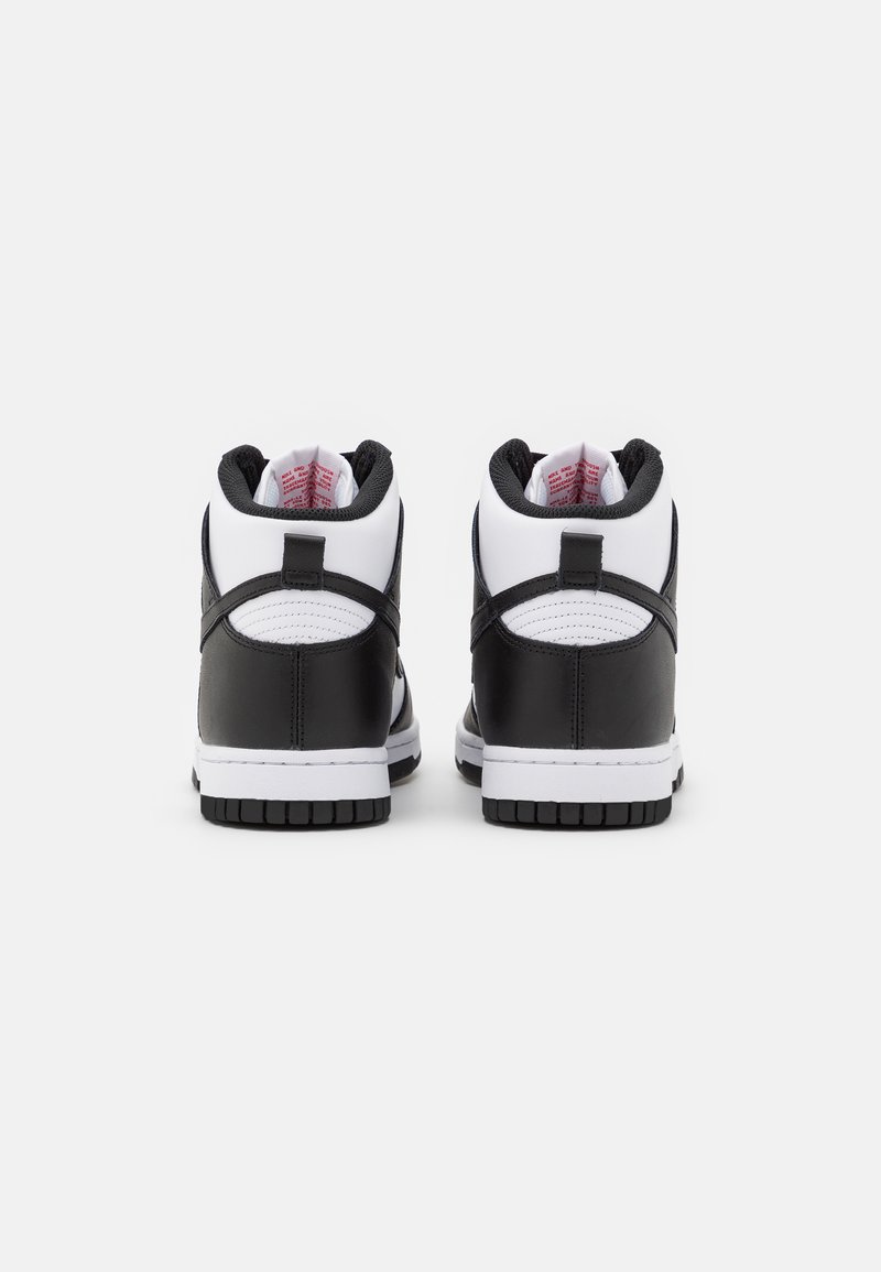 Zapatillas de caña alta con un exterior de cuero negro y acentos de textil blanco. La suela exterior es de goma negra con un patrón de agarre texturizado.