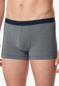 Boxers pour hommes en bleu marine avec des rayures verticales blanches, ceinture élastique portant la marque "Schiesser", design ajusté et texture lisse.
