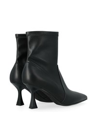 Bottines en cuir noir avec des bouts pointus et des talons hauts évasés, présentant des bords supérieurs cousus et une finition lisse.