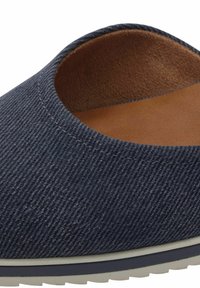Džínová slip-on obuv s kulatým otvorem, hnědým vnitřkem, bílou mezipodešví a strukturovaným tmavě modrým textilním vnějším povrchem.