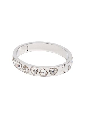 Brazalete de metal plateado con gemas claras en forma de corazón distribuidas uniformemente alrededor de su banda, mostrado con el cierre abierto sobre un fondo blanco.