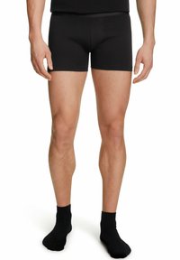 Pantaloni boxer neri in cotone con una vestibilità aderente, caratterizzati da una trama liscia e una cintura, accompagnati da calzini neri coordinati.