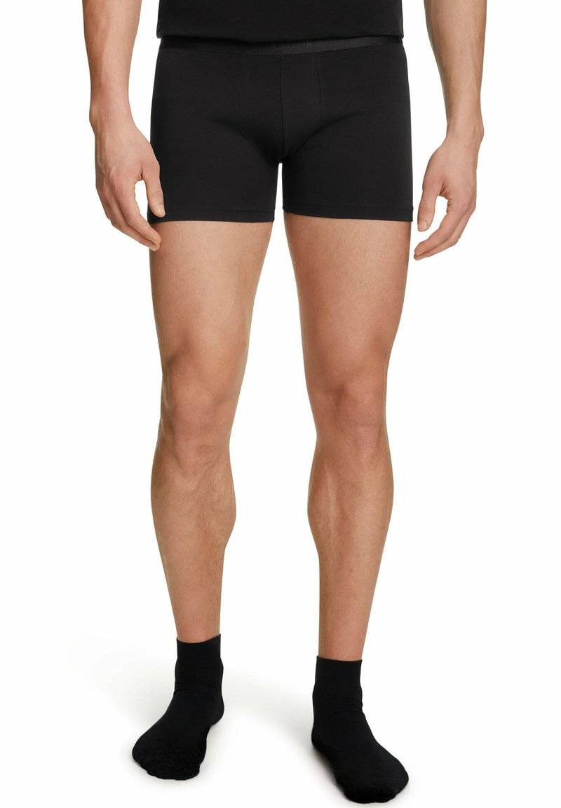 Pantaloni boxer neri in cotone con una vestibilità aderente, caratterizzati da una trama liscia e una cintura, accompagnati da calzini neri coordinati.