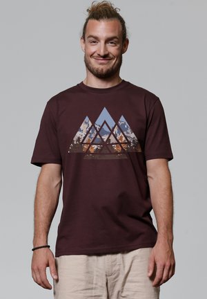 Bordeaux-kleurige katoenen t-shirt met een geometrische bergafbeelding in blauw, oranje en bruine tinten. Korte mouwen, ronde hals, ontspannen pasvorm.