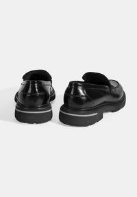 Schwarze Lackleder-Schuhe mit runder Zehenform, niedrigem Schnitt und einer strukturierten schwarzen Gummisohle mit einem grauen Akzentstreifen.