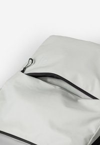 Lichtgrijze, zachte stoffen tas met een ritssluiting. Opvallende zwarte rits en trekband. Binnenin is er een gladde, niet-geverfde voering.
