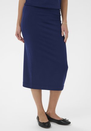 Navyblauer Strick-Midirock mit leicht ausgestelltem Saum, elastischem Bund und glatter Textur. Kombiniert mit schwarzen Ballerinas mit Schleifen.