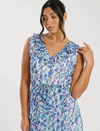 Blumendruckkleid in Blau- und lila-Tönen, mit V-Ausschnitt und Rüschenträgern, sowie einer gebundenen Taillenpartie. Transparente Stoffstruktur.