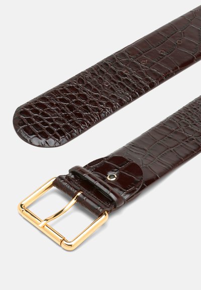 Tamsiai rudas krokodilo odos tekstūra juostas su blizgia auksine metaline sagtimi ir suderintu apkaustu, pasižyminti lygiu paviršiumi ir švariomis linijomis.