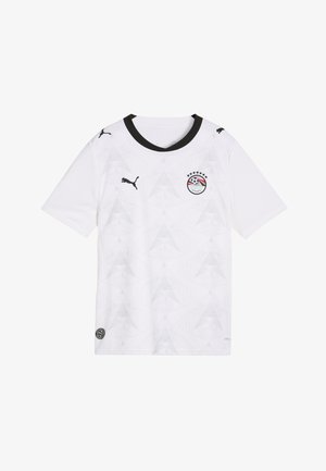 Fehér rövid ujjú futballmez fekete gallérral, fekete Puma logókkal a mellkason és az ujjakon, valamint csillagokkal díszített Egyiptomi Labdarúgó Szövetség emblémával a mellkason.