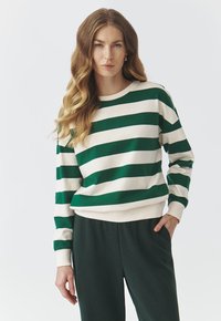 Sweatshirt rayé vert et crème avec manches longues et col rond. Doté de poignets et d'ourlet côtelés, fabriqué en tissu doux. Assorti à un pantalon vert foncé.