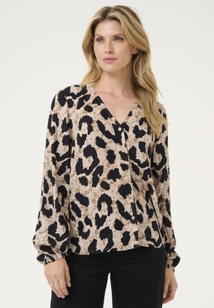 Blouse à manches longues et décolleté en V en tissu beige, ornée d'un imprimé léopard noir, avec des détails en boutons et des manches froncées.