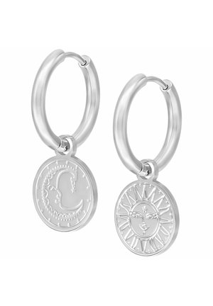 Silver hoop earrings with round pendants; one features a dragon design, the other a sun with a face and rays.